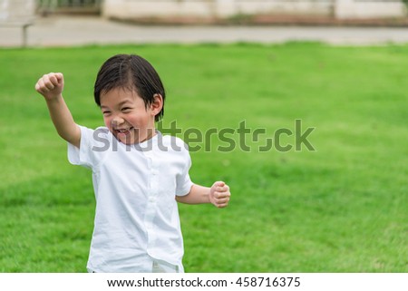 Close up of cute asian boy wear white shirt playing and happy in garden.