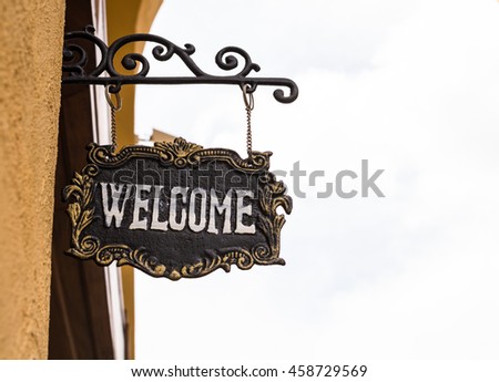 Welcome wooden sign board with rope hanging in front of the gate