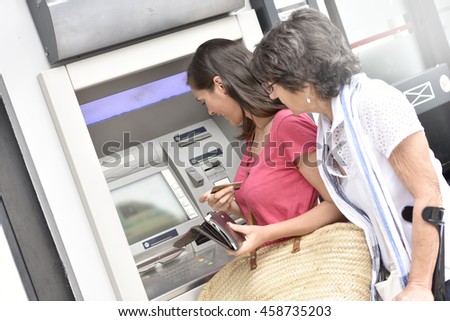 Home carer and disabled woman getting cash from bank