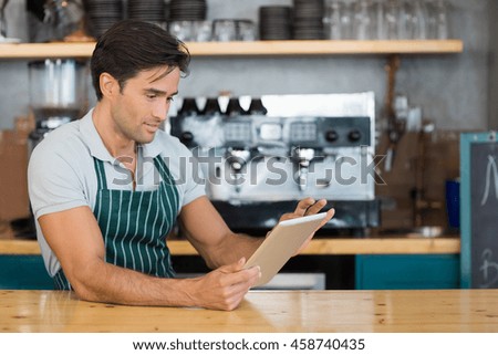 Waiter standing at counter using digital tablet