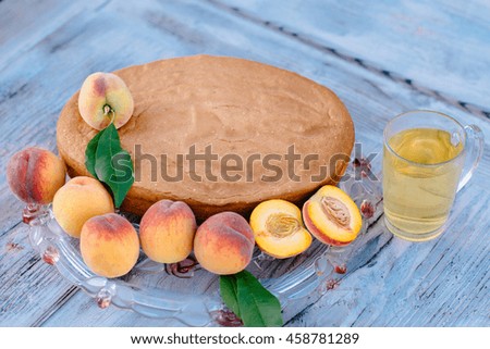 Fresh-baked sponge cake with peach slices on a large platter placed on the table