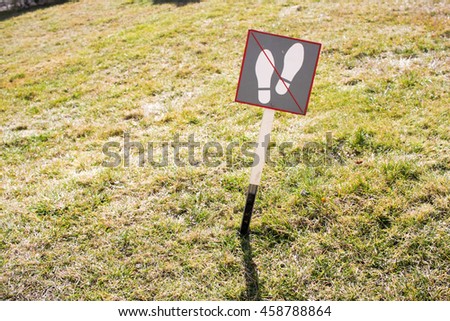 Don't walk on the grass sign on a crooked pole