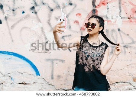 A young pretty girl spends his free time in the city. Photos on a background of graffiti