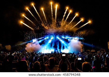 DJ Concert Festival with Special Effects Fireworks over the Silhouette Crowd Backlit Royalty-Free Stock Photo #458794348