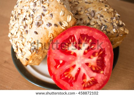 Composition of whole grain bread buns and tomato on wooden table background