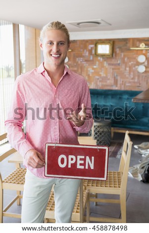 Portrait of restaurant manager holding open signboard in restaurant