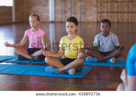 School kids meditating during yoga class in basketball court at school gym Royalty-Free Stock Photo #458892736