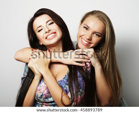 Two young girl friends standing together and having fun. Looking