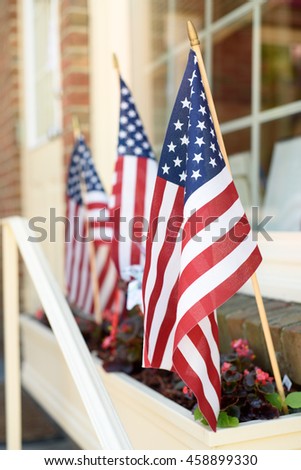American flags in a flower planter in front of a store window.