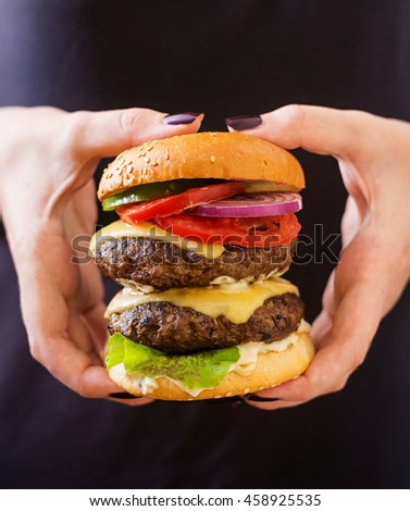 Big sandwich - hamburger burger with beef, cheese, tomato and tartar sauce in female hands
