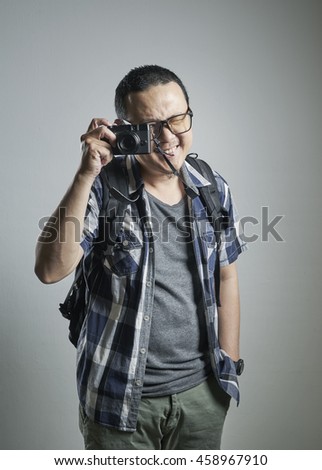 Travel concept. Studio portrait of young man taking a photograph.