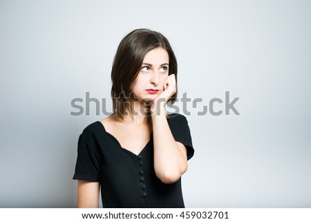 Young business woman props chin, studio photo isolated on a gray background