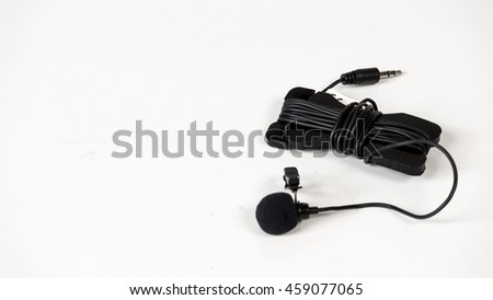 Black color small tie-clip on microphone lapel or lavalier. Isolated on white background. Slightly de-focused and close-up shot. Copy space.
