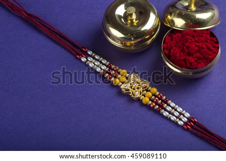 A Rakhi with rice grains and kumkum. An Indian festive background.