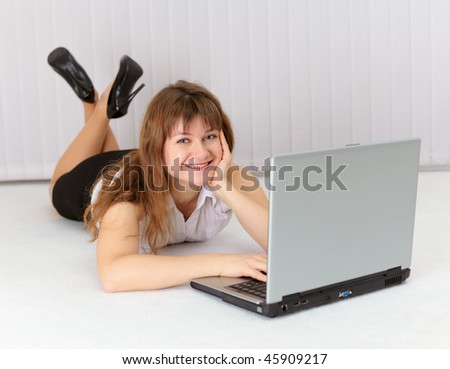 Happy young woman lying on the floor with laptop