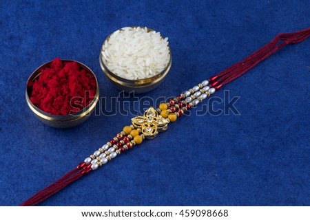 A Rakhi with rice grains and kumkum. Raksha Bandhan Festival. Indian festival background.