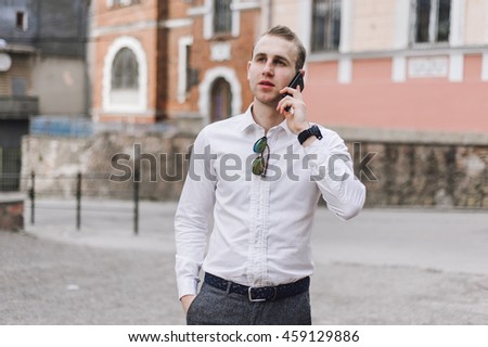 A man walks down the street with the phone and headset