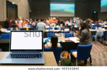 Blank screen laptop computer on the Abstract blurred photo of conference hall or seminar room with attendee background. Royalty-Free Stock Photo #459141844