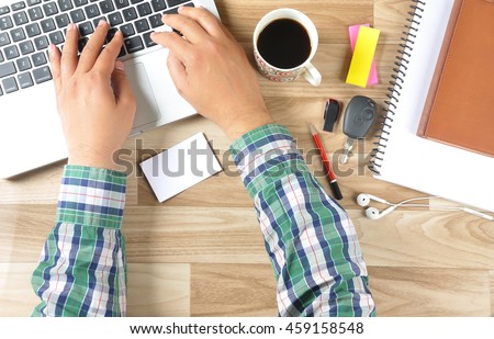 Customer looking for some online services with blank business card while working his office. The wooden table contains laptop, black tea, car key, pen drive, office articles and business card. Royalty-Free Stock Photo #459158548