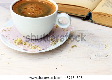 Full light composition with cup of fresh tasty coffee, vintage book with yellow shabby cover and paper. Concept for beautiful romantic morning theme with retro decor elements