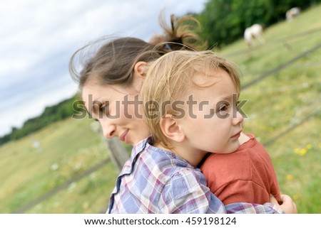 Mother and daugther cuddling in countryside