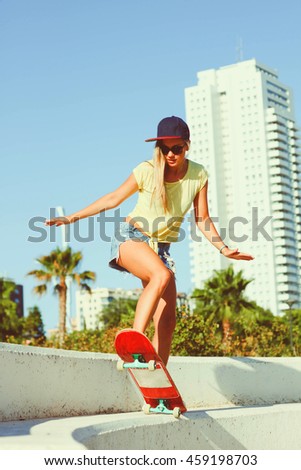 Beautiful girl riding on a skateboard and making tricksin sunny weather
