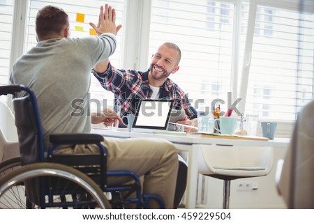 Handicap businessman giving high-five to colleague in creative office Royalty-Free Stock Photo #459229504