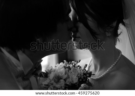 A black and white picture of a groom trying to kiss a bride