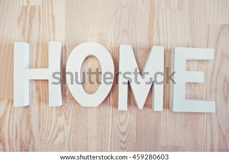 White wooden letters HOME at light wooden background