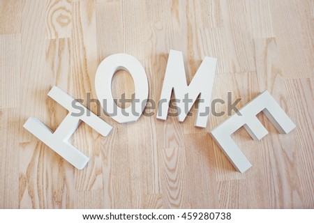 White wooden letters HOME at light wooden background