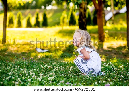 Little beautiful girl in the park in a white dress