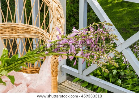 Wicker chair with flowers on outdoor patio.