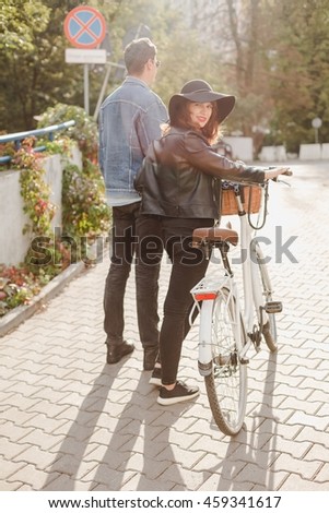 Man and the woman walking close together with white bicycle in urban area