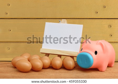piggy bank and canvas frame with wooden wall background