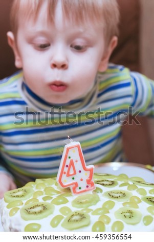 boy blows out the candles on the cake birthday four years