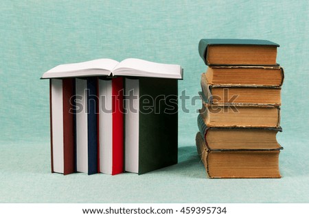 Open book, stack of hardback books on blue table. Back to school. Copy space.