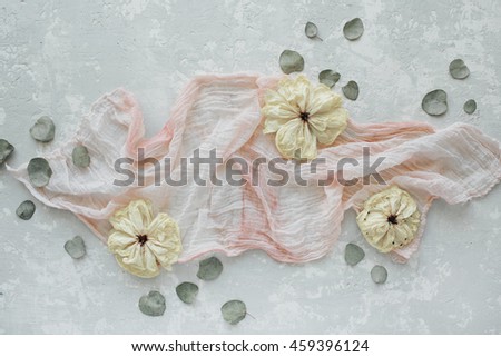 decorated composition with dry white tulips, eucalyptus petals and pink textile on concrete background. Flat lay, top view