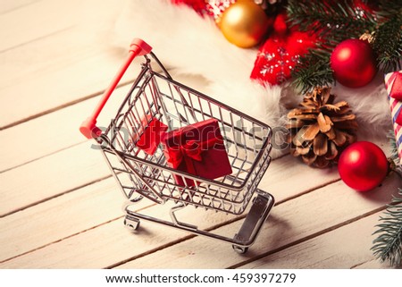 photo of the cup of coffee, shopping cart and christmas decorations on the white wooden background
