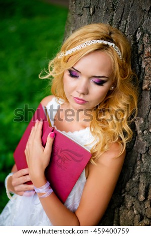 beautiful girl with a book sleeping near a tree