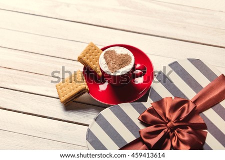 photo of the cup of coffee, cookies and heart shaped gift on the white wooden background