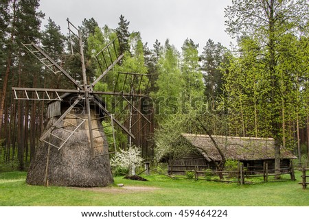 Traditional wooden windmill in ethnographic open-air museum in Riga, Latvia. Windmill covered by straw. Latvian Ethnographic Open Air Museum. Royalty-Free Stock Photo #459464224