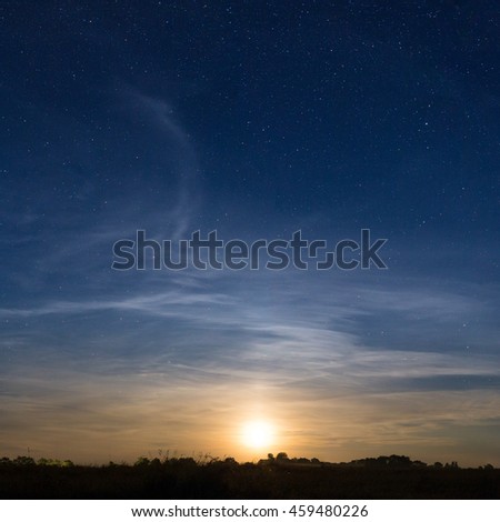 Rising moon in dark blue sky with stars over the meadow. Natural astronomy background