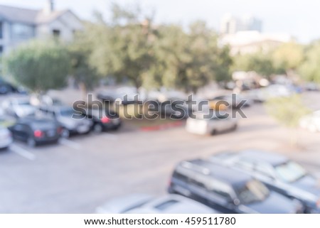 Abstract blurred elevated view of apartment garage with full of covered parking, cars and green trees at multi-floor residential buildings in Houston, Texas. Aerial view crowded parking. Vintage look.