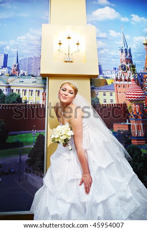 Happy bride in a wedding dress against the wall with a picture