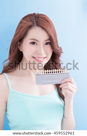 Beautiful young woman with health teeth and hold teeth whitening tool. Isolated over blue background, asian beauty