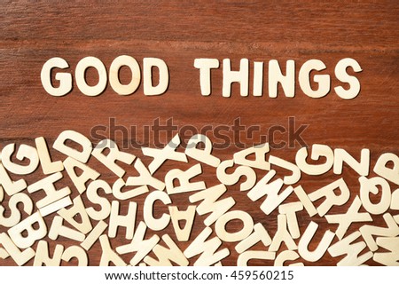 Word good things made with block wooden letters next to a pile of other letters over the wooden board surface composition