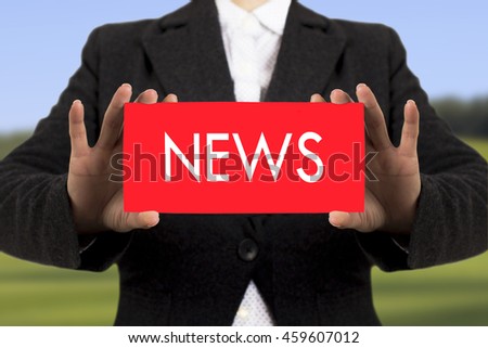 Businesswoman in a black jacket shows a card with the inscription news. Selective focus.
