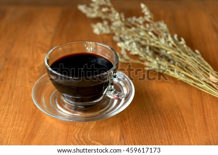Americano black coffee. Coffee cup on the wooden background. Espresso mixed with hot water. Hot Coffee. Dried flowers are placed in the rear. Background blur.