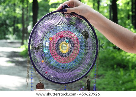 photo of a dreamcatcher made by hand, with using threads, beads and feathers rooster
