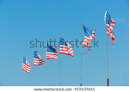 Five American flags blowing in the wind on blue sky